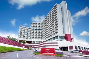 Un gran edificio blanco con coches aparcados delante. en Okinawa Grand Mer Resort, en Okinawa City