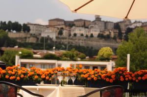 una mesa con copas de vino y flores naranjas en el balcón en Hotel Excelsior San Marco, en Bérgamo