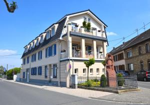 een wit gebouw met een balkon in een straat bij Boardinghouse am Welzbach in Gau-Algesheim