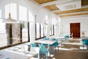 a restaurant with white tables and blue chairs at Bungalows Mar Menor, paz a orillas del mar in San Javier