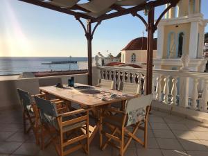 a wooden table and chairs on a balcony with the ocean at Traditional House of Diafani in Karpathos