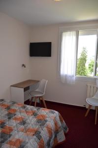 a bedroom with a bed and a desk and a television at Hôtel Montfort in Lourdes