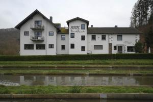 a white building with a pond in front of it at Hotel-Restaurant Forellenzucht in Burgen