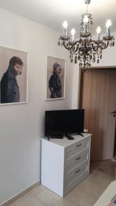 Habitación con tocador, TV y lámpara de araña. en Virág Wellness Villa, en Pécs