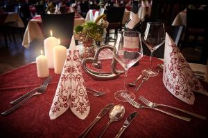 a table with a red table cloth with candles and wine glasses at Hotelgasthof zur Sonne in Bad Gögging