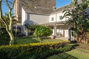 a white house with a garden and trees at City Lodge Hotel Durban in Durban