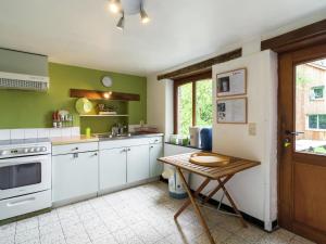 cocina con paredes verdes, armarios blancos y mesa en Pleasant holiday home with garden in Ciney, en Ciney