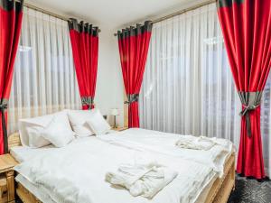 a bedroom with red curtains and a bed with towels on it at Machajówka in Białka Tatrzańska