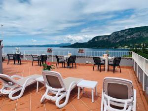 a patio with chairs and tables and a view of the water at Hotel Conca D'Oro ***S in Garda