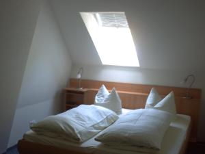 Bett mit weißen Kissen und Licht in einem Zimmer in der Unterkunft Haus Dachsberg Todtmoos in Todtmoos