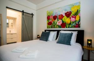 1 dormitorio con 1 cama blanca y una pintura en la pared en Slapen bij Jesse, en Broek in Waterland
