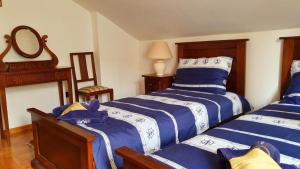 um quarto com 2 camas com lençóis azuis e brancos em Villa Rava Hotel & restaurant em Rava