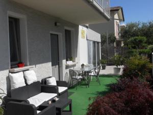 un patio con tavolo, sedie e prato verde di B&B Villa Flora a Peschiera del Garda