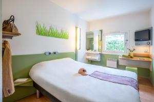 Schlafzimmer mit einem großen weißen Bett und einem Fenster in der Unterkunft ibis budget Thionville Yutz in Basse-Yutz