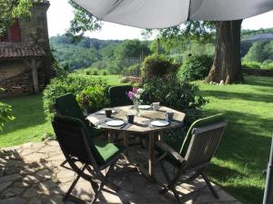 a table with chairs and an umbrella on a patio at Les Temps des Sources in Veyrines-de-Domme