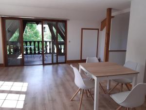 uma sala de jantar com uma mesa de madeira e cadeiras brancas em Chambre de la Vigne em Blesmes