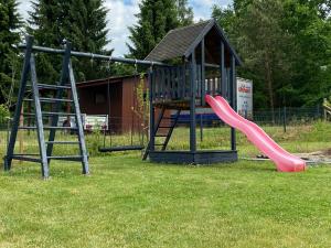 a playground with a pink slide in the grass at Ferienhaus “ Lille Hyggehytte“ in Altenmedingen