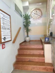 a staircase with a clock and a potted plant at Piccolo Hotel in Rosignano Solvay
