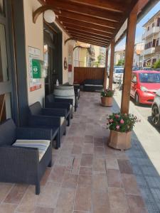 a restaurant patio with couches and flowers on a sidewalk at Piccolo Hotel in Rosignano Solvay