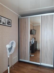 a sliding glass door with a fan in a room at Однокімнатна in Shepetivka