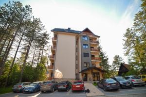 a tall building with cars parked in a parking lot at Mountain Residence Zlatibor - Apartman Sara 1 in Zlatibor