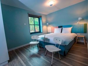 a bedroom with a bed and a table and chairs at Hotel Kapellerput Heeze-Eindhoven in Heeze