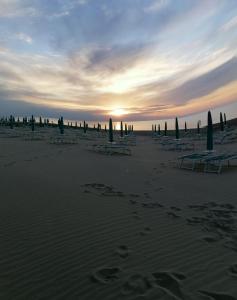 a beach with chaise lounges and umbrellas in the sand at Albergo 2 Pini in Rodi Garganico