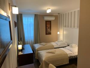 a hotel room with two beds and a television at Pension Eden in Želiezovce