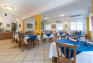 a restaurant with tables and chairs with blue table cloth at Hotel Sasselli in Cesenatico