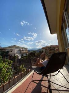une personne assise dans une chaise sur un balcon dans l'établissement Appartamento Villa Circe, à Taormine