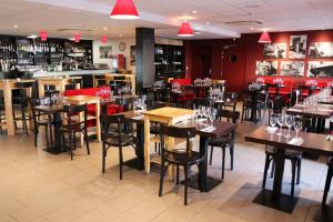 a restaurant with wooden tables and chairs and a bar at Le Quarré Hôtel Bistrot in Bruguières
