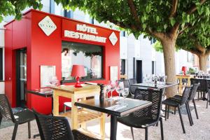 a restaurant with tables and chairs and a red building at Le Quarré Hôtel Bistrot in Bruguières