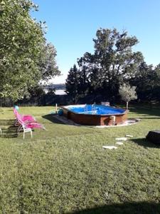 une cour avec une chaise rose et une piscine dans l'établissement Chalet 4 personnes, à Montolieu