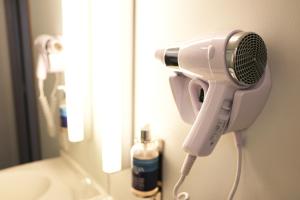 a blow dryer on a wall next to a mirror at Le Quarré Hôtel Bistrot in Bruguières