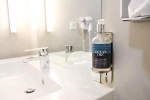 a bottle of soap is sitting on a bathroom sink at Le Quarré Hôtel Bistrot in Bruguières +16 photos