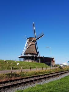 a windmill in the middle of a field next to a train track at De Stadshoeve in Medemblik