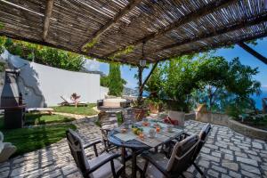 eine Terrasse mit einem Tisch und Stühlen unter einer Pergola in der Unterkunft Casa Elena in Praiano