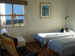 um quarto com duas camas e uma cadeira e uma janela em Guesthouse Pétursborg em Akureyri