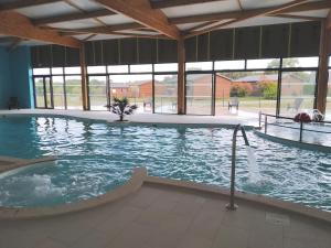 una gran piscina cubierta con bañera de hidromasaje en Le Domaine de la Héchaie en Marzan