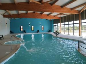 una gran piscina cubierta con agua en un edificio en Le Domaine de la Héchaie en Marzan