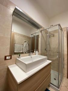 La salle de bains est pourvue d'un lavabo blanc et d'une douche. dans l'établissement Appartamento Villa Circe, à Taormine