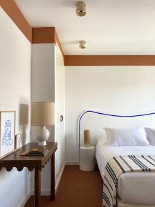a bedroom with a bed, desk, lamp, and mirror at Hôtel Le Sud in Juan-les-Pins