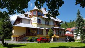 a large yellow building with a clock on it at Penzión Jesenský in Vysoke Tatry - Tatranska Lomnica.