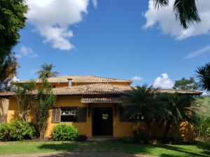 une maison jaune avec des palmiers devant elle dans l'établissement Hotel Fazenda Minas Real, à Simão Pereira