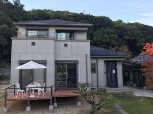 Casa con terraza con mesa y sombrilla en MIKOTO HOUSE en Kashū