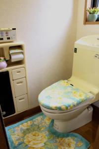 een badkamer met een toilet en een bloemkleed bij MIKOTO HOUSE in Kashū
