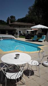 einen Tisch und Stühle neben einem Pool in der Unterkunft Le Petit Moulin Tournesol BnB in Sainte-Soline