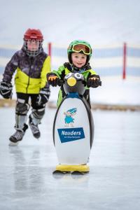 un niño pequeño montando una motocicleta de juguete en el hielo en Apart Alte Straße, en Nauders