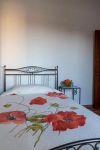 un letto con una coperta con fiori rossi sopra di Ca' Masini a San Giovanni in Marignano