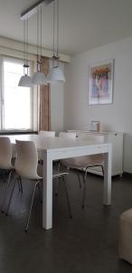 a white dining room with a white table and chairs at Elite 1 in Koksijde